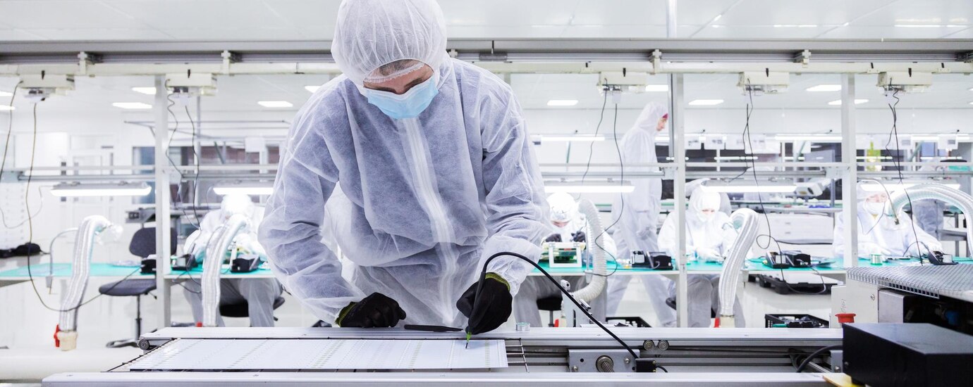 focus-is-factory-worker-white-lab-suit-black-latex-gloves-face-mask-working-with-soldering-iron-other-workers-are-background-horizontal-picture_645730-619