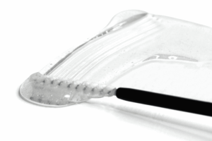 Clear eyelash treatment texture shown with a cosmetic applicator