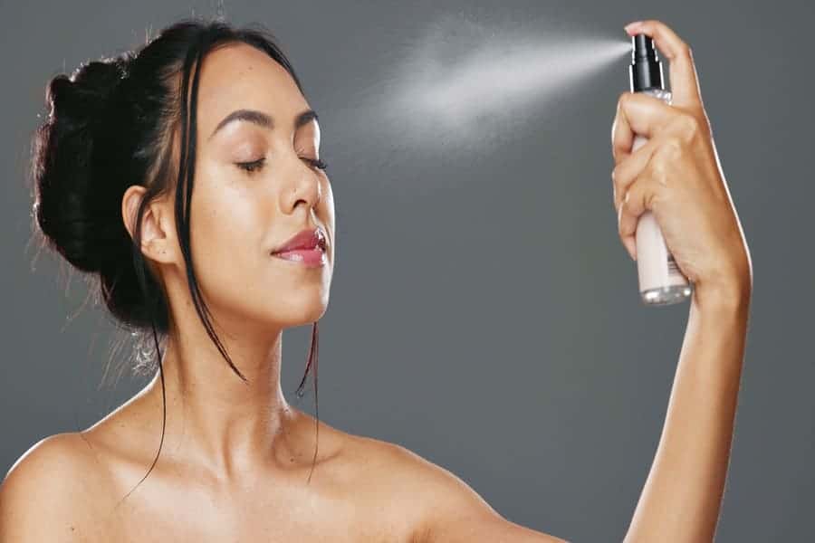 Woman spraying a hydrating face mist on her skin
