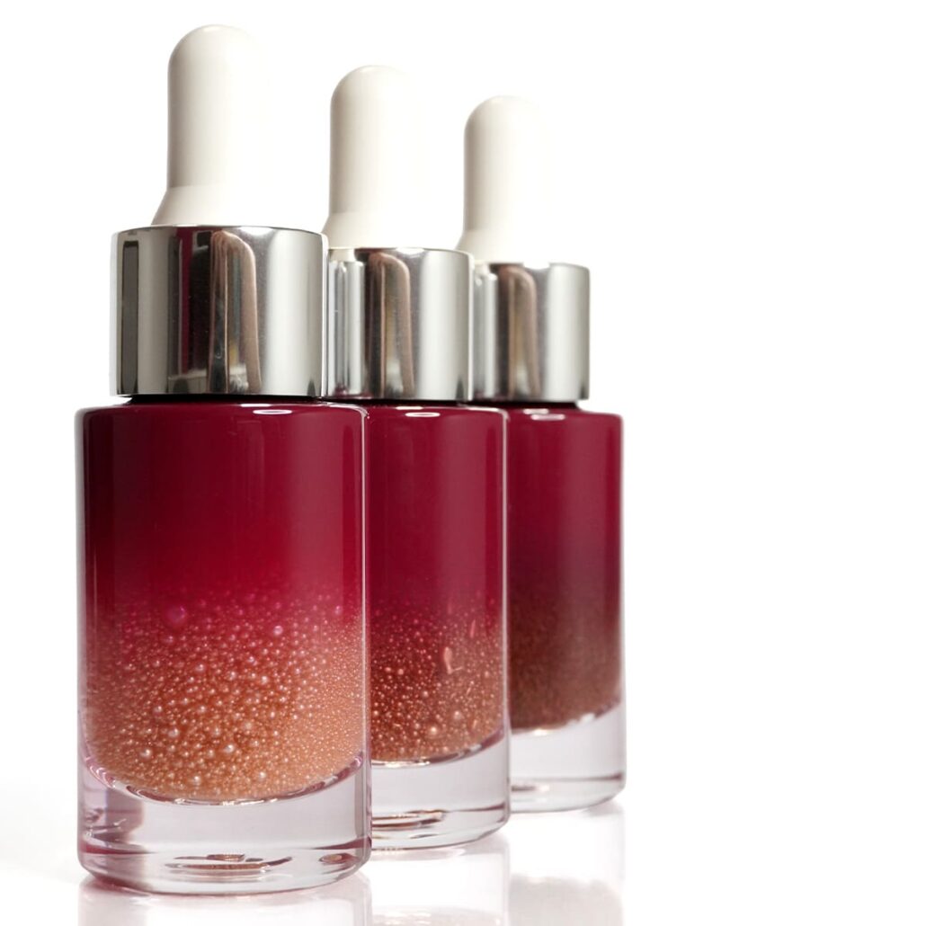 Three dropper bottles with suspended golden spheres in clear liquid